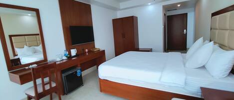 Une chambre d’hôtel avec un grand lit, un bureau, une chaise, une télévision et une armoire.