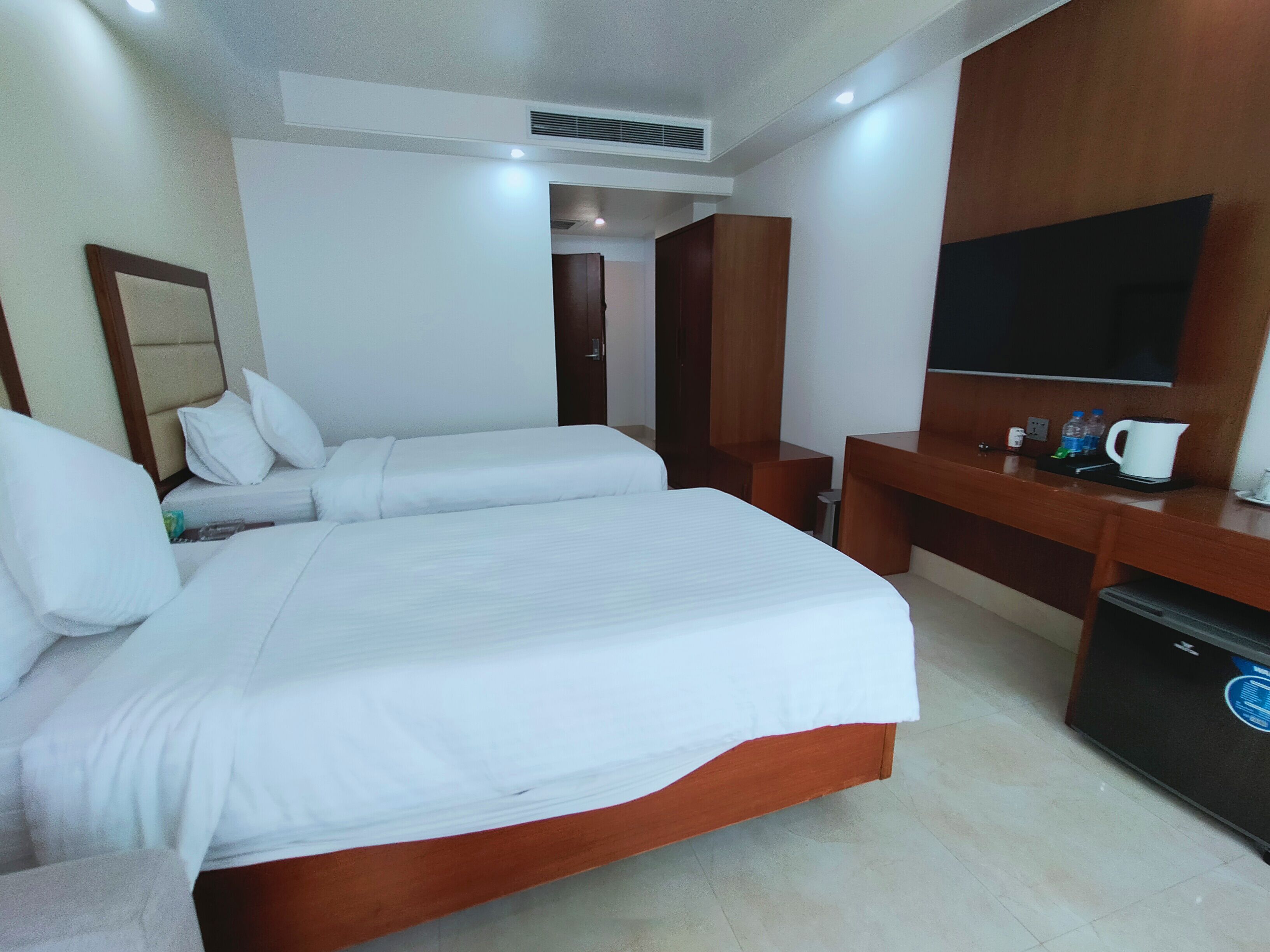 Una habitación de hotel con una cama grande, un escritorio, un televisor y un espejo.