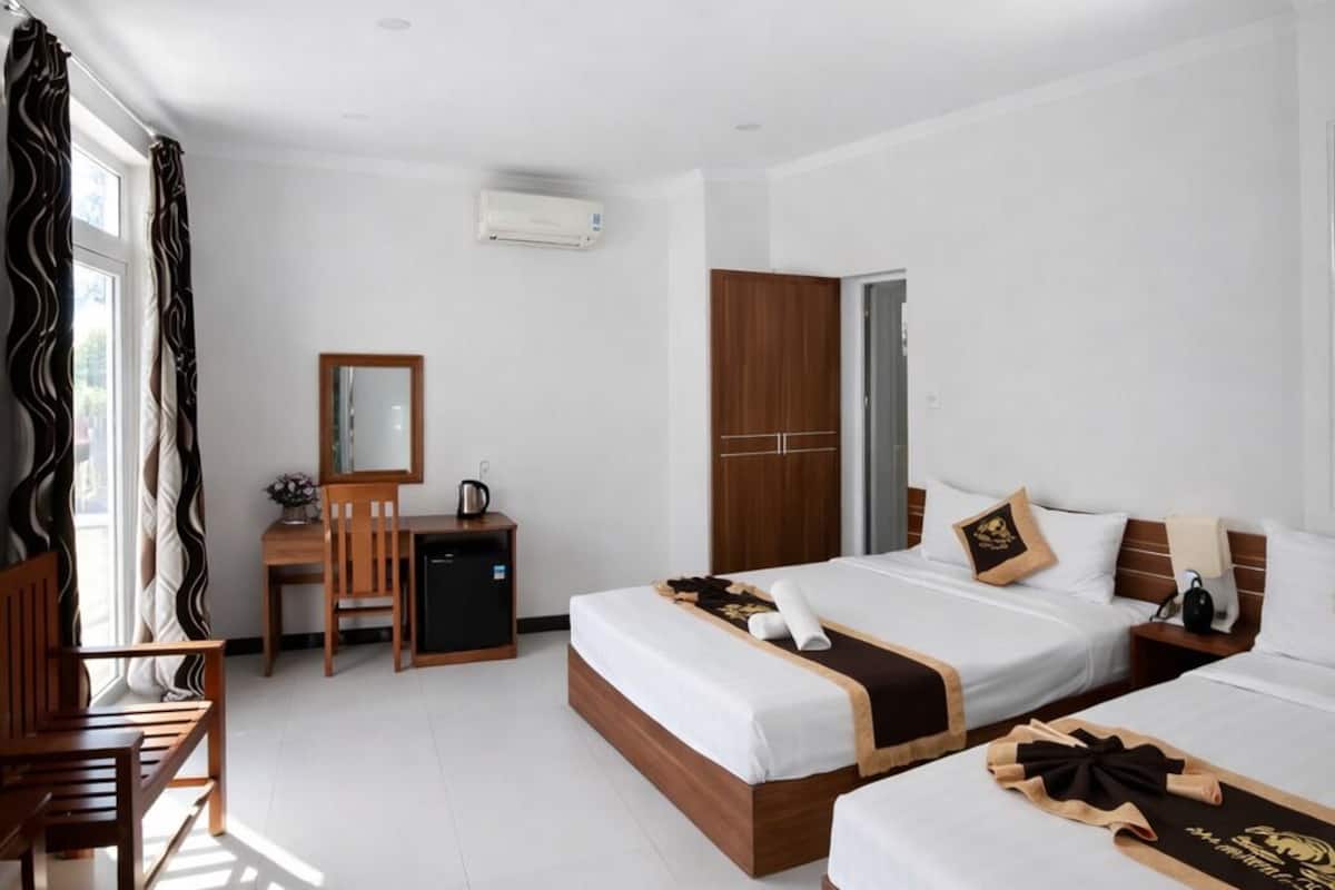 Quarto de hotel com duas camas, uma escrivaninha, um guarda-roupa e ar condicionado.