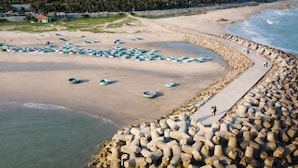A beach with boats and a rocky breakwater. - Pham Gia Hotel Mui Ne (Mui Ne)