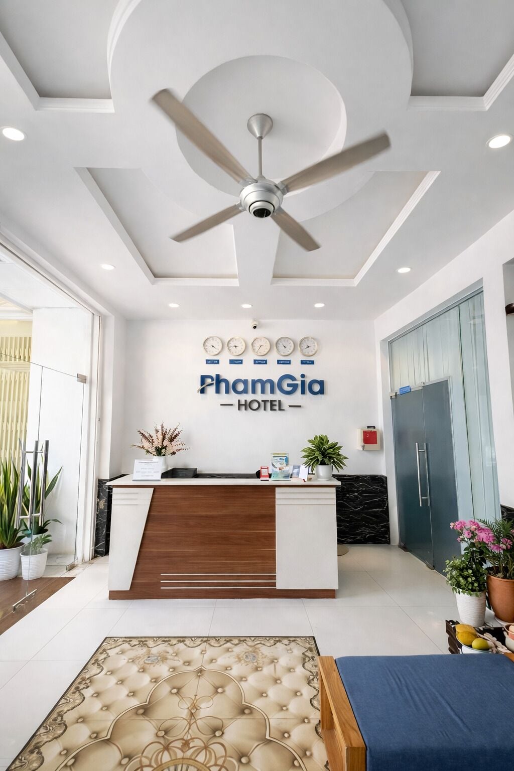 Zona de recepción de un hotel con ventilador de techo, mostrador de recepción y un cartel que dice 'PhamGia HOTEL'.