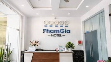 Zona de recepción de un hotel con ventilador de techo, mostrador de recepción y un cartel que dice 'PhamGia HOTEL'.