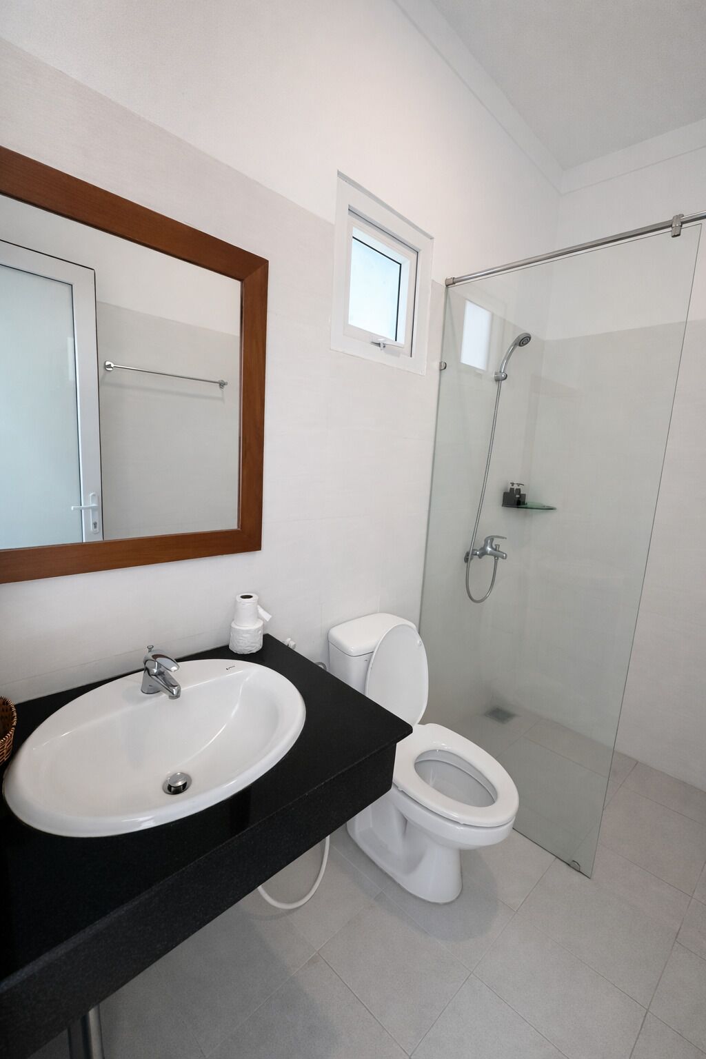 A bathroom with a white sink, toilet, and glass shower enclosure.
