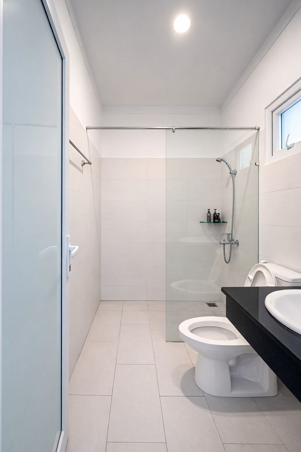Une salle de bain moderne avec une douche à parois de verre, des toilettes blanches et un plan de toilette noir avec un lavabo.