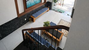 A modern interior with a staircase, a framed artwork, a bench, and a view of the outside. - Pham Gia Hotel Mui Ne (Mui Ne)