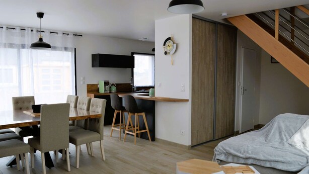 Un espace de vie moderne comprenant un coin repas, une cuisine et un escalier.