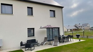 Un bâtiment moderne doté d’un patio aménagé avec du mobilier d’extérieur et un barbecue.