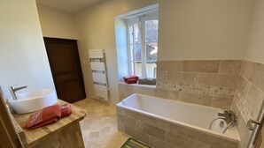 Ein Badezimmer mit einer Badewanne, einem Waschbecken, einem Fenster und einem Handtuchhalter.
