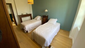 Ein Schlafzimmer mit zwei Betten, einem Nachttisch, einer Lampe und einer Pendelleuchte.