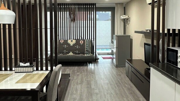 A modern kitchen with a dining area, wooden flooring, and a view through a glass door.