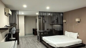 A modern hotel room with a large bed, a desk, a chair, and a wardrobe.