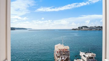 Vista de un puerto deportivo con un barco amarrado en primer plano y una costa distante con edificios.