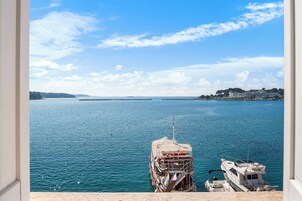 Vista de un puerto deportivo con un barco amarrado en primer plano y una costa distante con edificios.