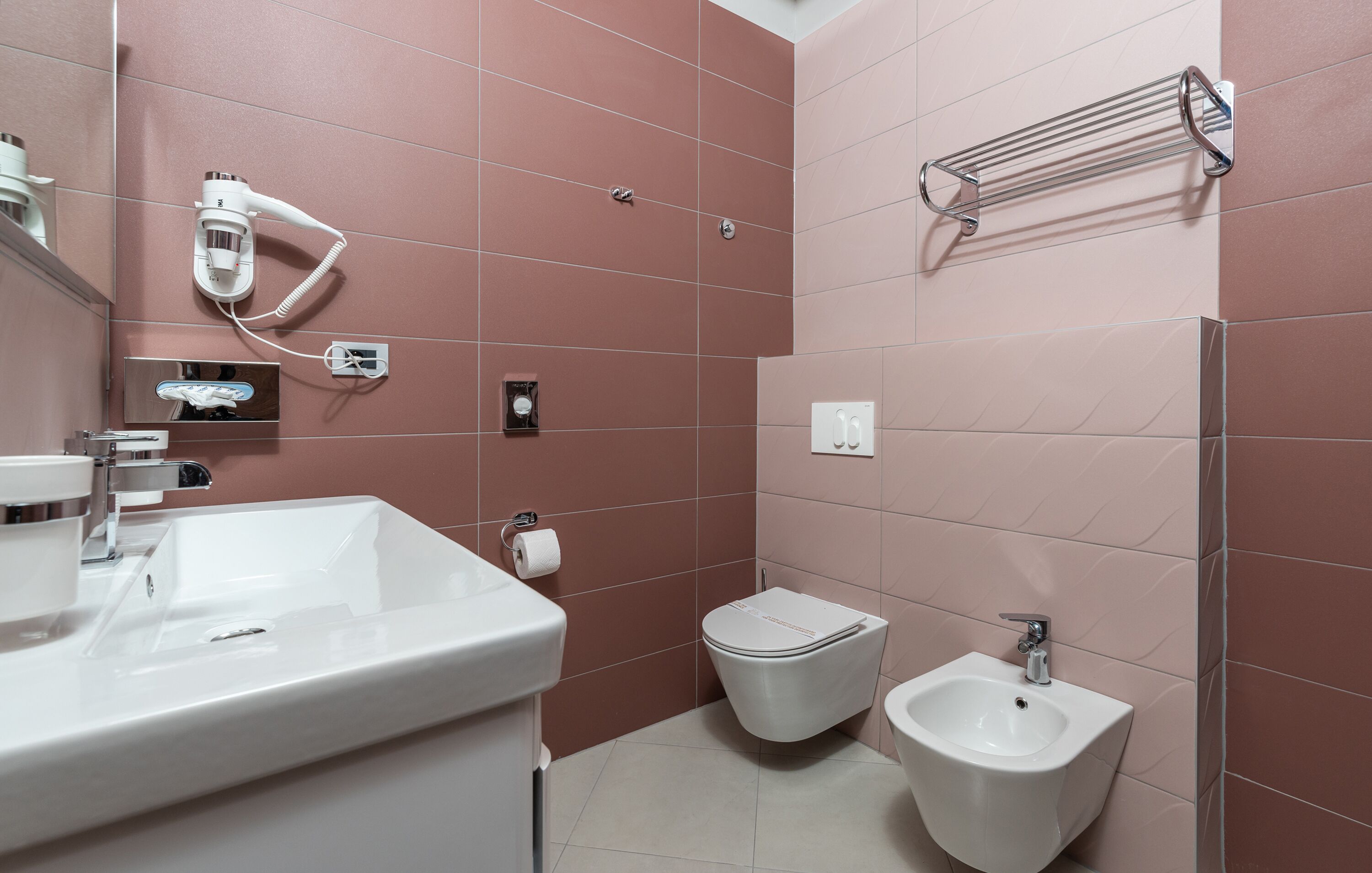 A modern bathroom with a white sink, a toilet, and a bidet.