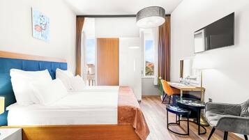 Habitación de hotel con cama, escritorio, silla, televisor y ventana.