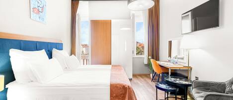 Habitación de hotel con cama, escritorio, silla, televisor y ventana.