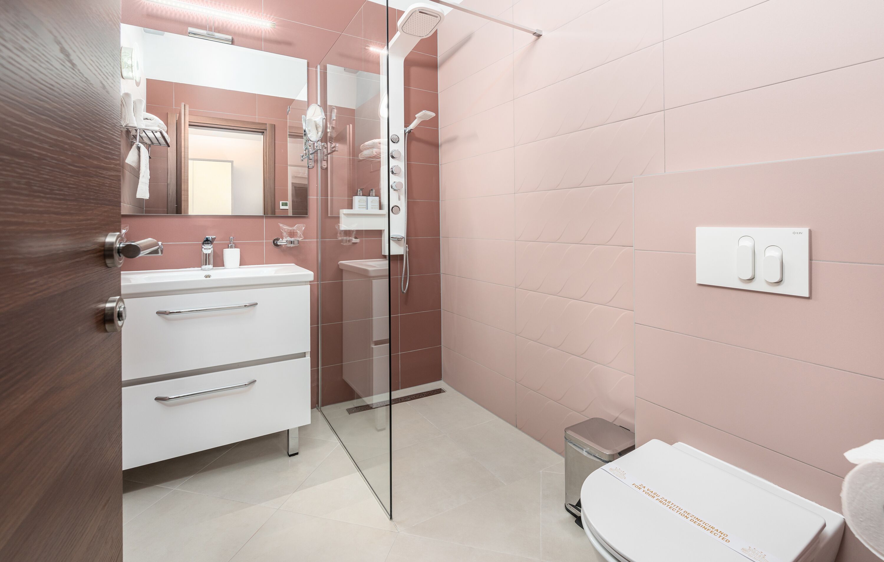 Un baño moderno con cabina de ducha de vidrio, un lavamanos blanco y un mueble de tocador con cajones.