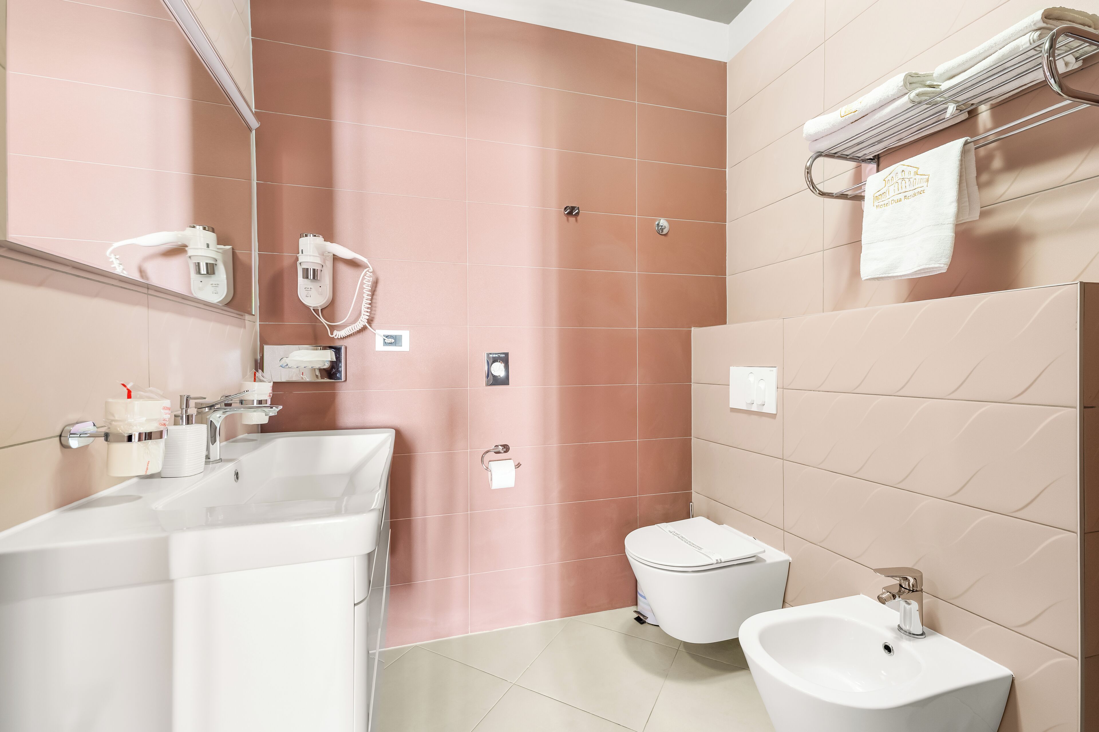Un baño moderno con lavamanos, inodoro, bidé y toallero.