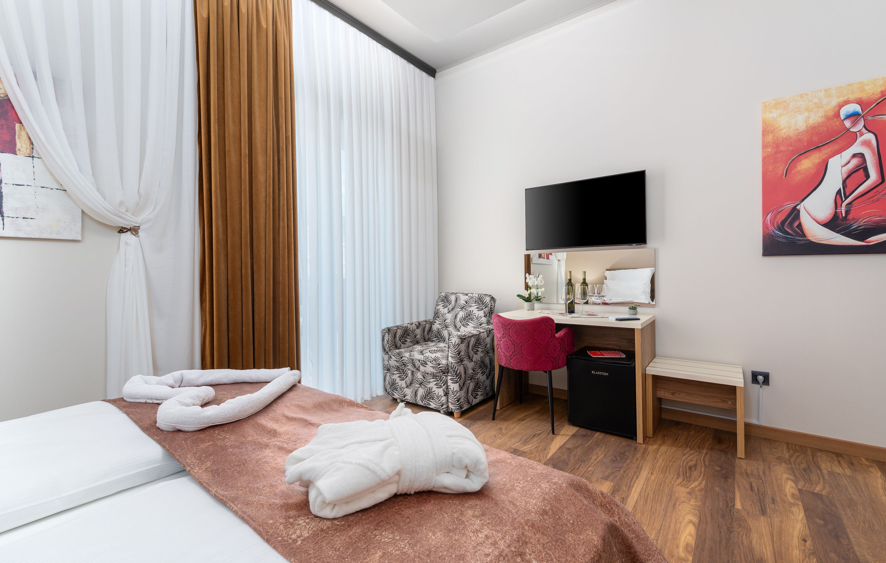 A hotel room with a bed, a desk, a chair, and a TV.