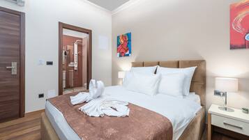 Una habitación de hotel con una cama, una mesita de noche, un cuadro en la pared y la puerta del baño.