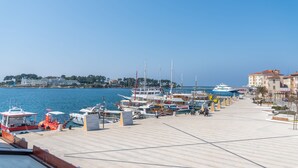 A marina with various boats docked, a clear sky, and buildings in the background. - Hotel Dua Residence (Porec)