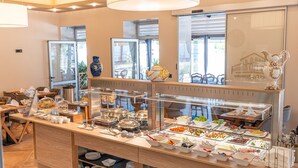 A buffet setup with various food items and a coffee station in a well-lit room with large windows. - Hotel Dua Residence (Porec)