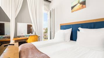 A hotel room with a bed, a desk, a chair, and a window with curtains.
