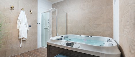 Une salle de bain moderne dotée d’un grand jacuzzi, d’une douche à parois de verre et d’un mur décoré d’un motif en imitation bois.