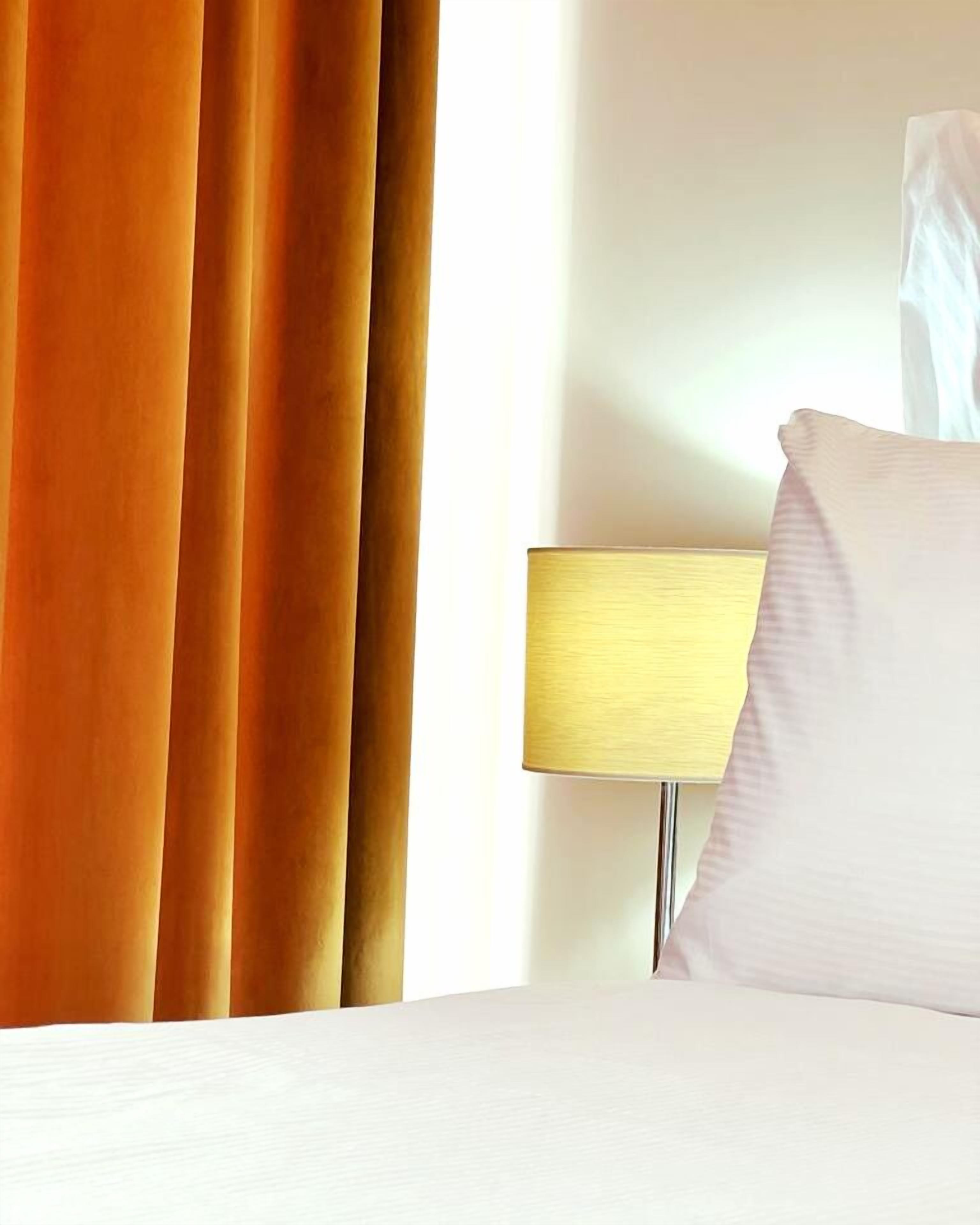 Ein Hotelzimmer mit einem Bett, einer Lampe und Vorhängen.