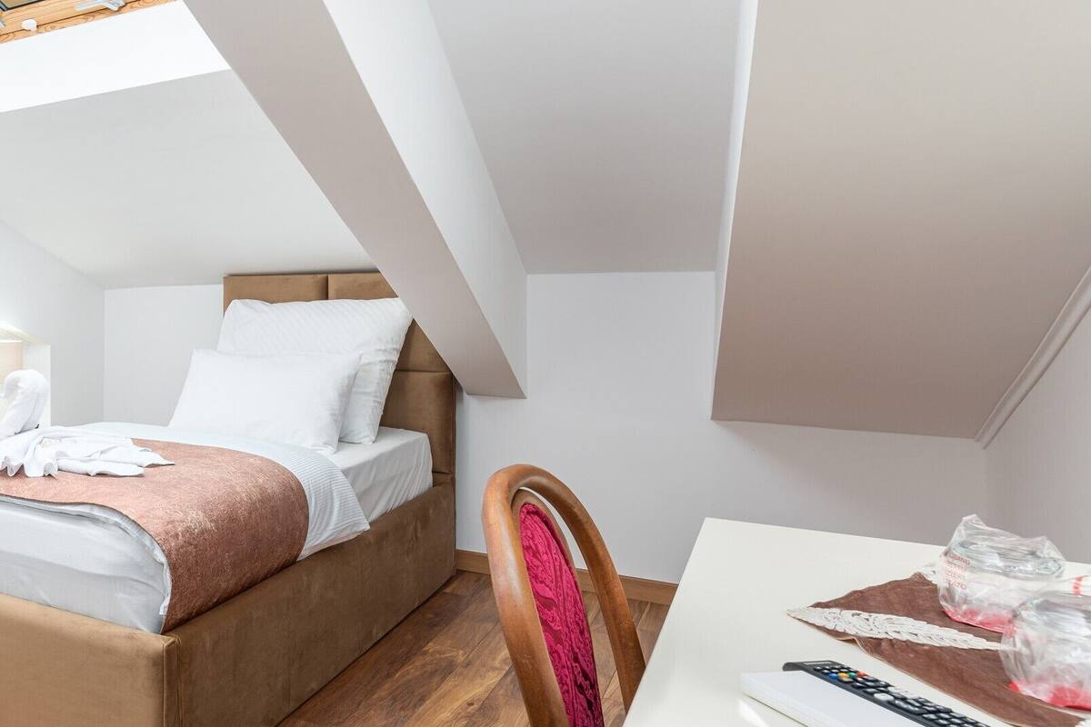 A modern bedroom with a loft-style bed, wooden flooring, and a dining area with a table and chairs.