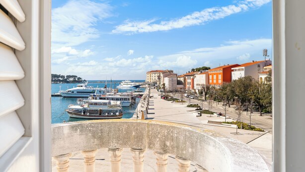 A coastal town with a marina, buildings with red and white facades, and a clear sky. - Hotel Dua Residence (Porec)