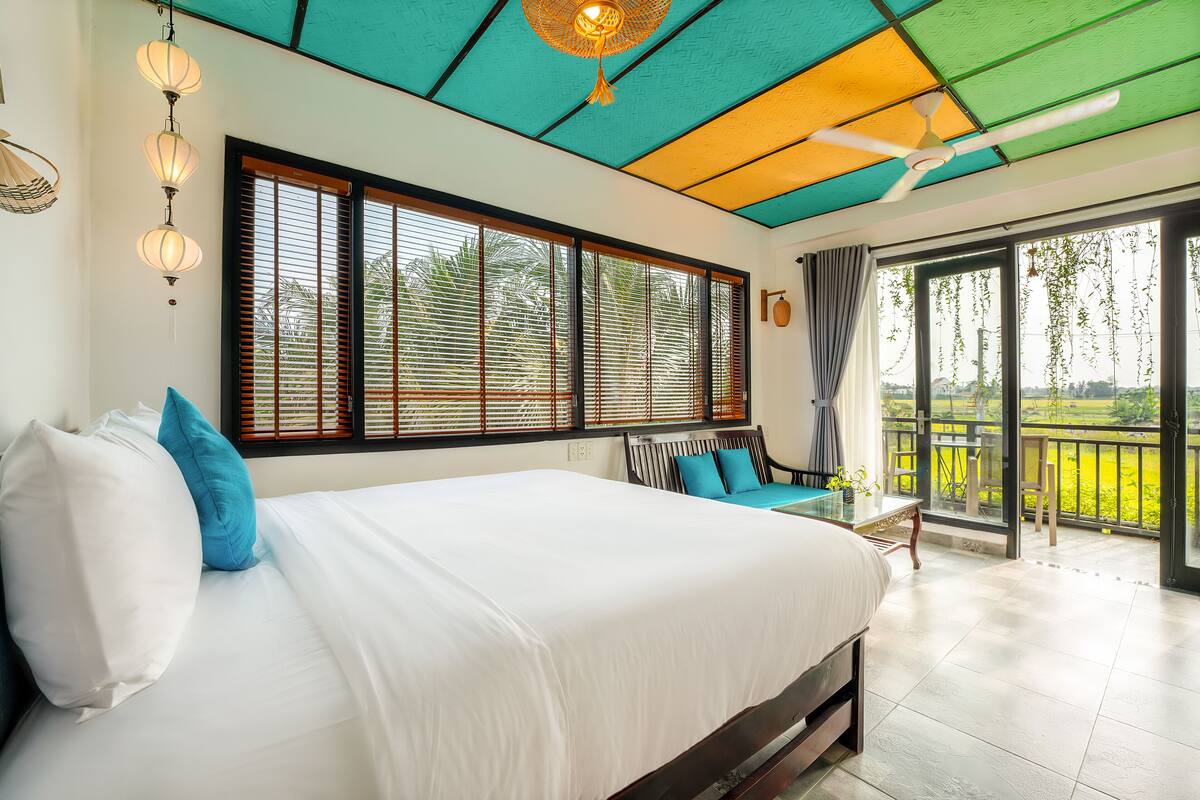 Ein Schlafzimmer mit einem großen Bett, einem Deckenventilator und Blick auf einen Balkon.