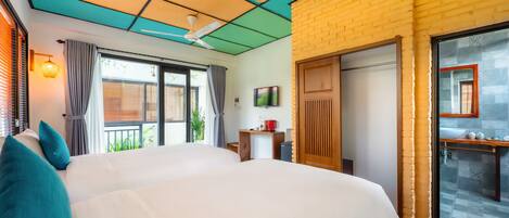 A hotel room with a large bed, a ceiling fan, a TV, and a bathroom with a sink and mirror.