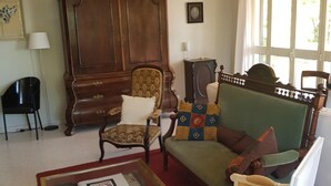 A traditional living room with a green sofa, a wooden cabinet, and a patterned armchair. - Belvilla by OYO Villa Roma Sabina (Borgonuovo)