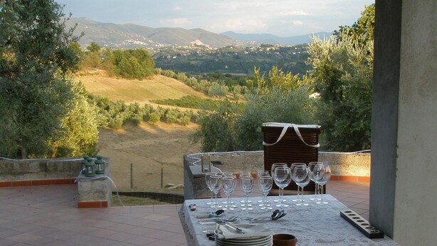 An outdoor dining area with a table set for six, overlooking a scenic landscape with hills and trees. - Belvilla by OYO Villa Roma Sabina (Borgonuovo)