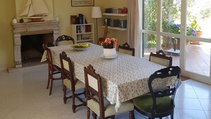 A dining room with a fireplace, a table with a floral tablecloth, and chairs. - Belvilla by OYO Villa Roma Sabina (Borgonuovo)