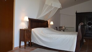 A bedroom with a wooden bed, two bedside tables with lamps, a nightstand, a wooden wardrobe, and a white canopy over the bed. - Belvilla by OYO Villa Roma Sabina (Borgonuovo)