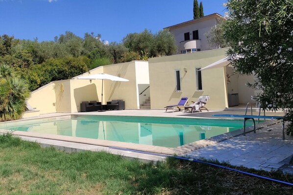 Une maison moderne dotée d’une piscine, d’un espace salon extérieur et d’un escalier menant à l’étage supérieur.