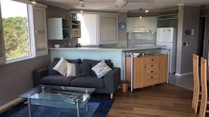 A compact living space with a sofa, coffee table, kitchenette, and a dining area.