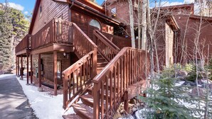Une cabane en bois dotée d’un porche couvert et d’un escalier menant à l’entrée principale.