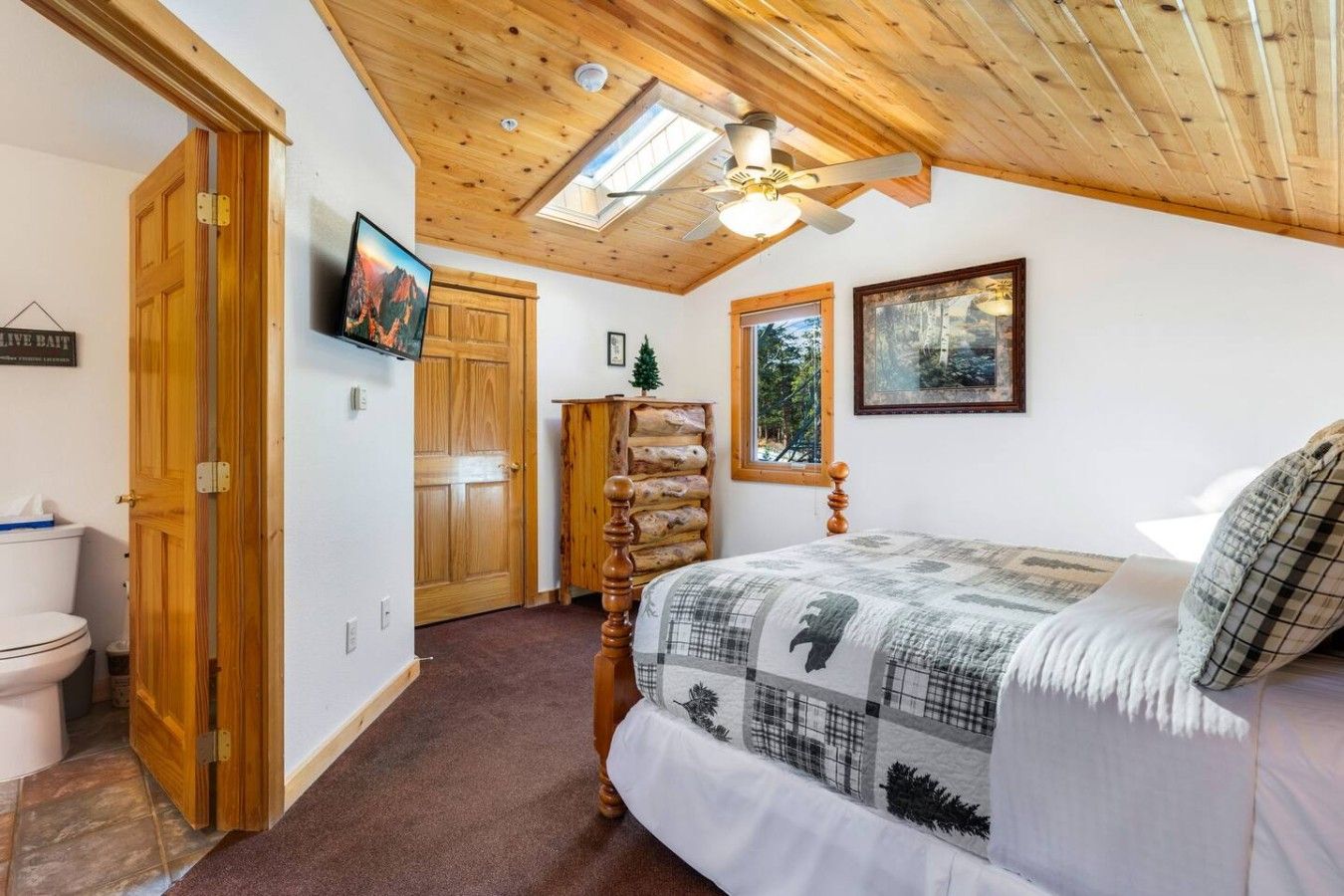 A bedroom with a bed, a wooden ceiling, a window, and a door.