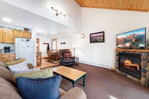 A living room with a fireplace, a television, and a dining area with wooden furniture.