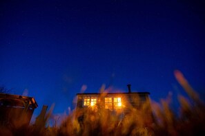 A house with a chimney and windows lit at night.