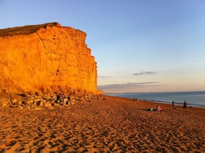 Een strand met een hoge klif, zandstrand en mensen die van de omgeving genieten.