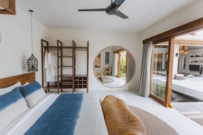 Relax in a spacious room with a large bed, round mirror, and comfortable seating area.