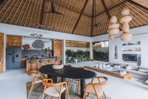 Relax in this open-plan living space with a high ceiling, featuring a central dining area, kitchen, and comfortable seating area.