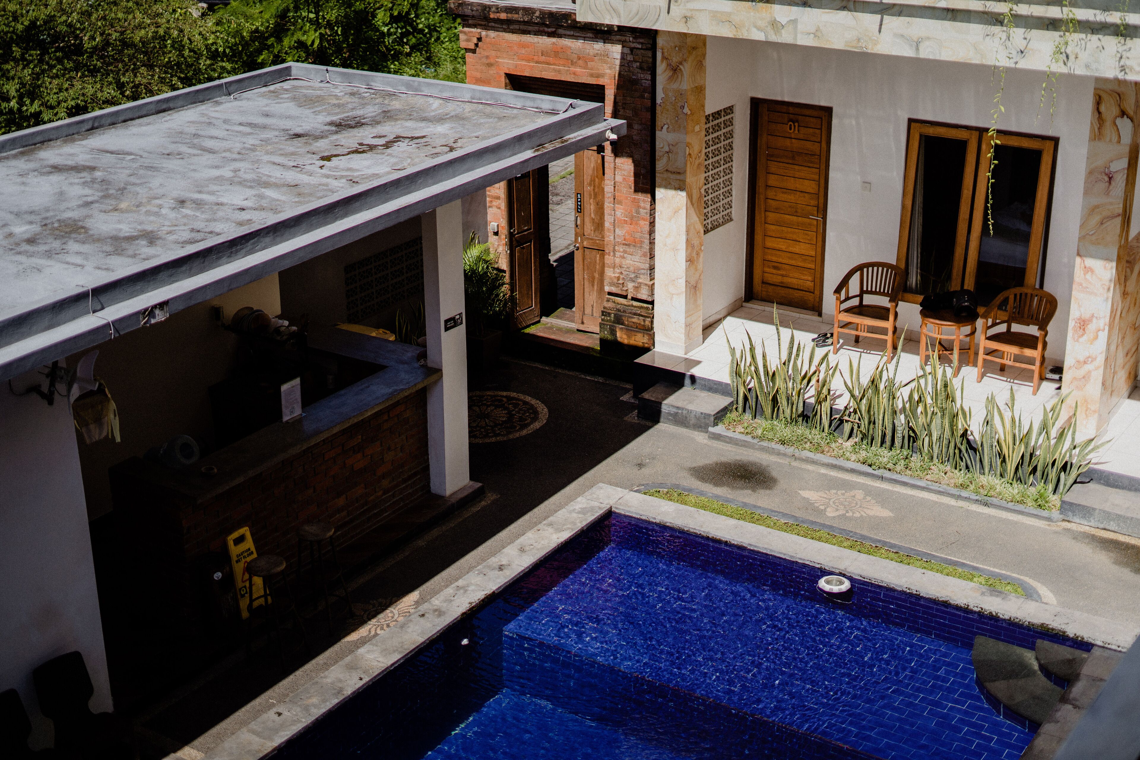 A rooftop bar with a pool, a wooden door, and a seating area with chairs.