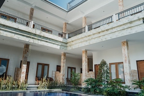 A multi-level atrium with marble columns, balconies, and a pool area.