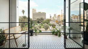 Een balkon met uitzicht op een stadsgezicht, met gebouwen en een palmbom.
