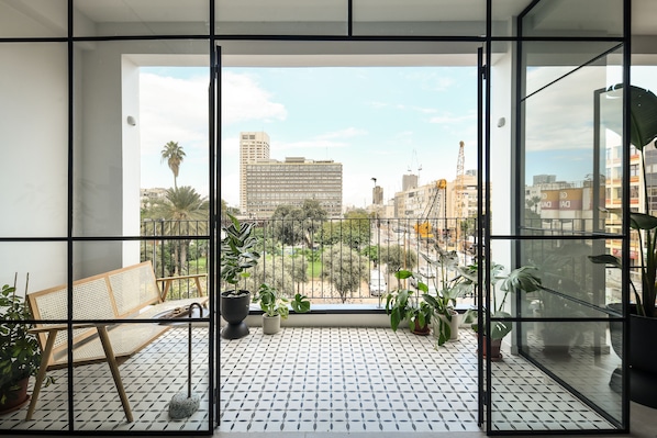 Un balcón con vistas a un paisaje urbano, incluyendo edificios y una palmera.